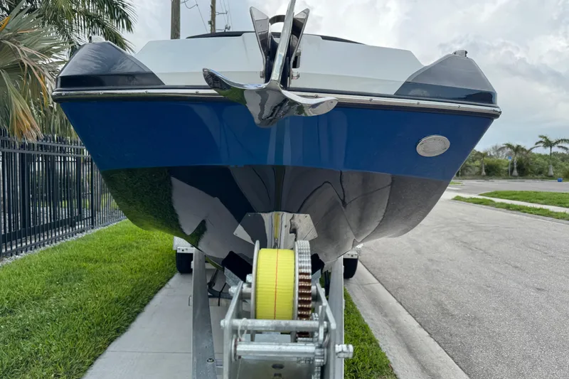 Slide: The Image of 2022 Scarab 285 ID boat on trailer, blue hull, parked roadside. - 12