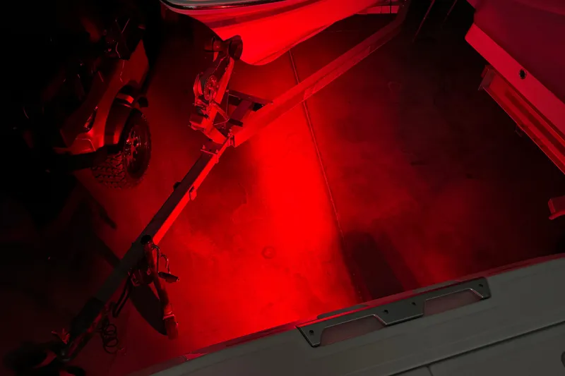 Slide: The Image of Red-lit Scarab 285 ID boat trailer in a dimly lit garage, 2022 model. - 123