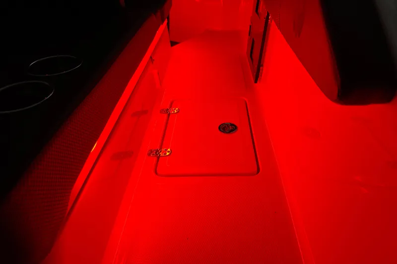 Slide: The Image of Red-lit interior of 2022 Scarab 285 ID boat, featuring sleek design and storage compartment. - 126