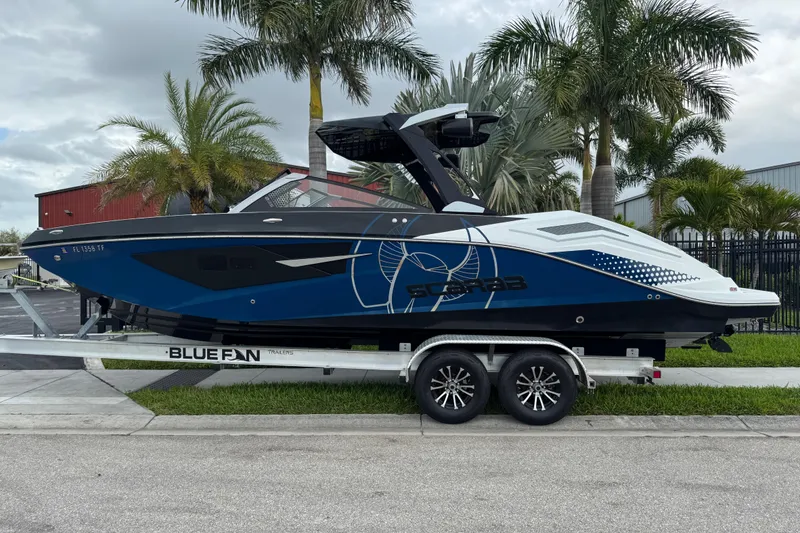 Slide: The Image of 2022 Scarab 285 ID boat on trailer, parked near palm trees. - 3
