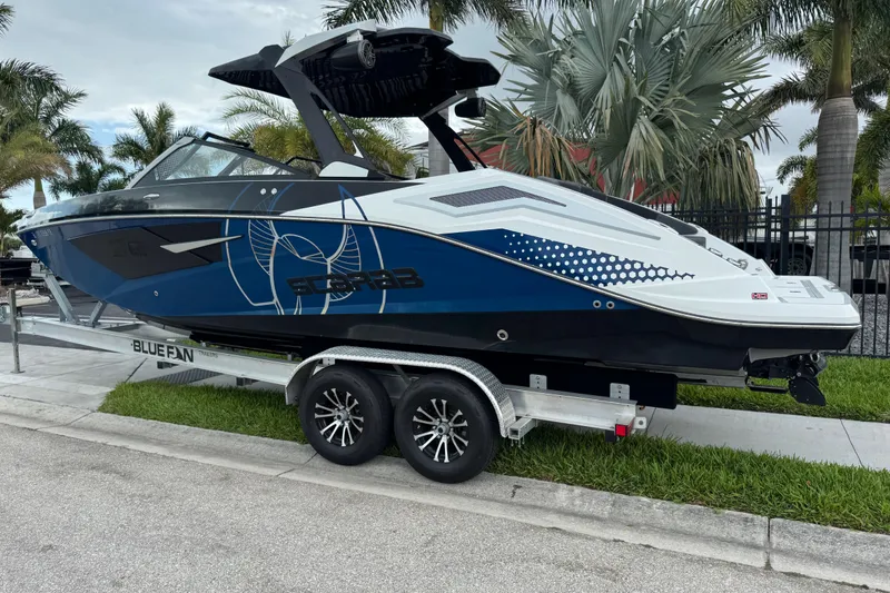 Slide: The Image of 2022 Scarab 285 ID boat on trailer, parked near palm trees. - 4