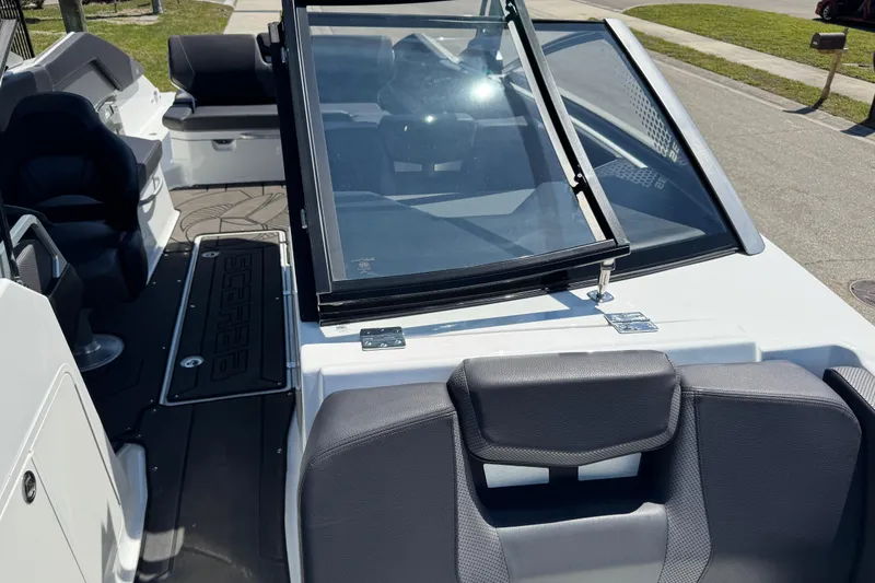 Slide: The Image of 2022 Scarab 285 ID boat interior with seating and windshield, parked on a sunny street. - 86