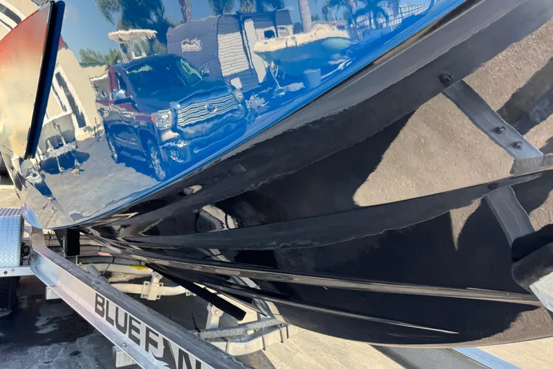 Slide: The Image of 2022 Scarab 285 ID boat on trailer, reflecting nearby vehicles and buildings. - 91