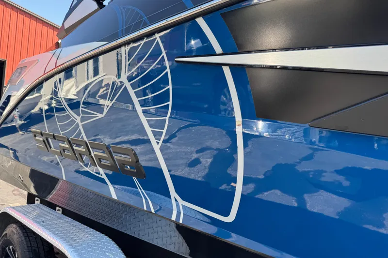 Slide: The Image of 2022 Scarab 285 ID boat with sleek blue and black design, parked outdoors. - 94
