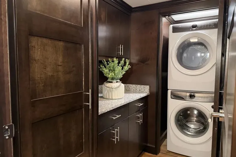Slide: The Image of Laundry area in 2019 Sumerset houseboat with stacked washer-dryer and dark wood cabinets. - 14