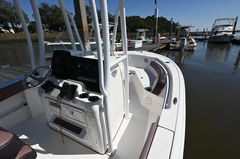 Slide: The Image of 2017 Tidewater 210 LXF boat docked at marina, featuring helm and seating area. - 13