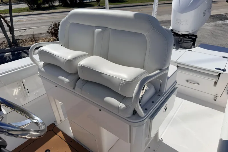 Slide: The Image of 2019 Everglades 253 Center Console boat with white cushioned seating and steering wheel. - 12