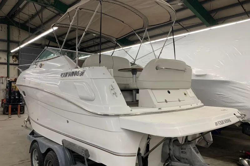Slide: The Image of 2003 Four Winns 248 Vista boat in a storage facility, showcasing its sleek design and canopy. - 3