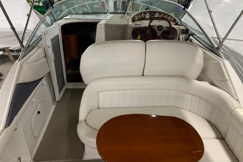 Slide: The Image of Interior of 2003 Four Winns 248 Vista boat with white seating and wooden table. - 6