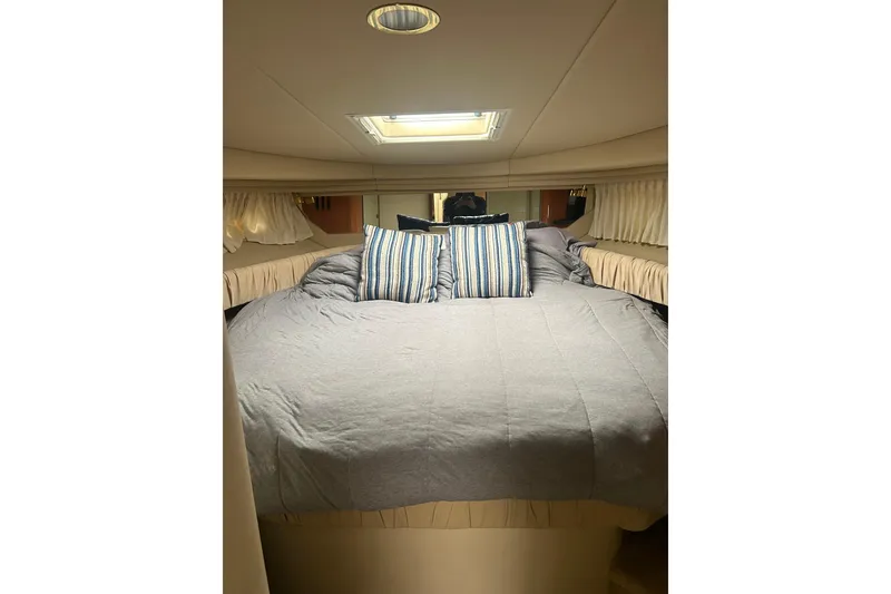 Slide: The Image of Cozy cabin interior of 2001 Sea Ray 380 Sundancer with plush bedding and striped pillows. - 16