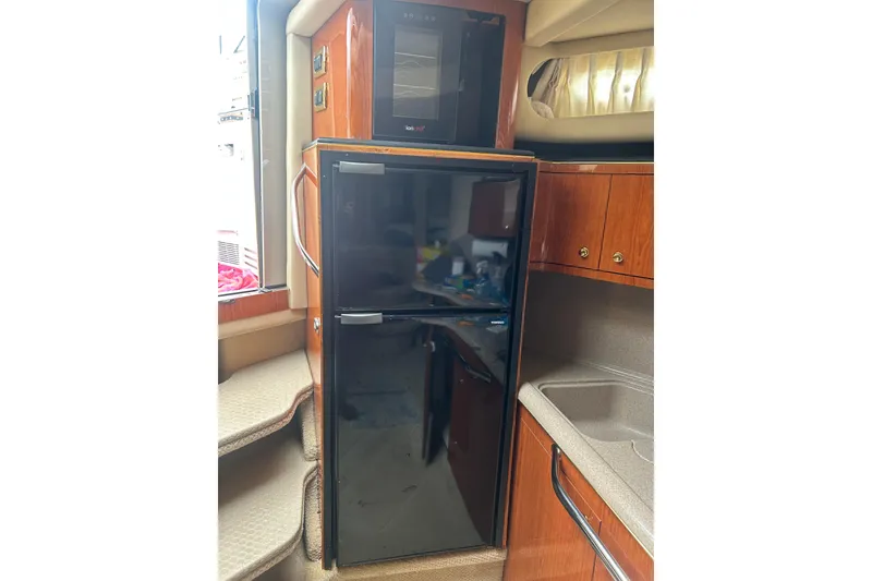 Slide: The Image of Interior of 2001 Sea Ray 380 Sundancer with fridge and wooden cabinetry. - 17