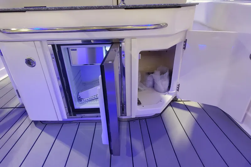 Slide: The Image of 2023 Chaparral 300 OSX boat interior with open mini fridge and storage compartment. - 13