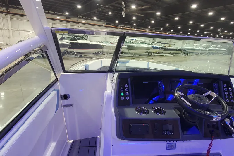 Slide: The Image of 2023 Chaparral 300 OSX boat cockpit with illuminated dashboard and steering wheel in showroom. - 23