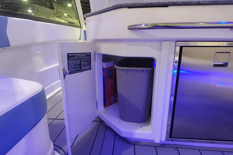 Slide: The Image of 2023 Chaparral 300 OSX boat interior with open storage compartment and trash bin. - 38