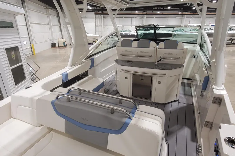Slide: The Image of 2023 Chaparral 300 OSX boat interior with seating and kitchenette in a showroom. - 4
