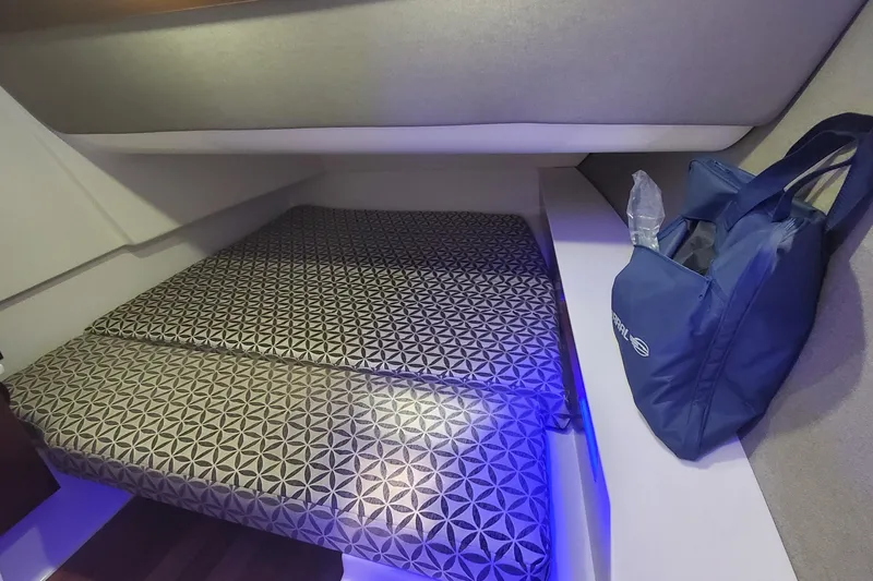 Slide: The Image of 2023 Chaparral 300 OSX cabin interior with patterned bedding and blue bag. - 41