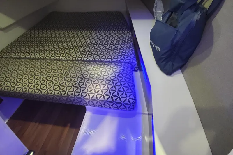 Slide: The Image of 2023 Chaparral 300 OSX cabin interior with patterned bedding and ambient blue lighting. - 42