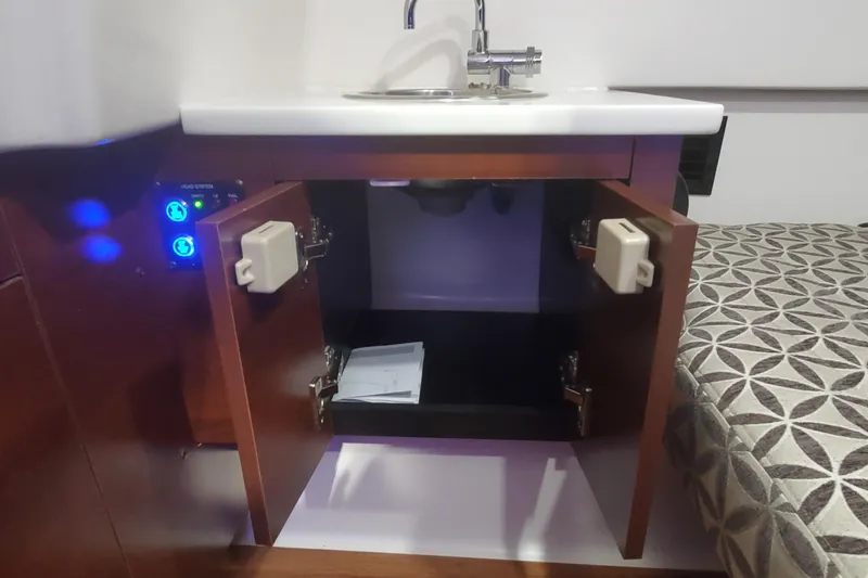 Slide: The Image of 2023 Chaparral 300 OSX interior with open cabinet, sink, and patterned cushion. - 44