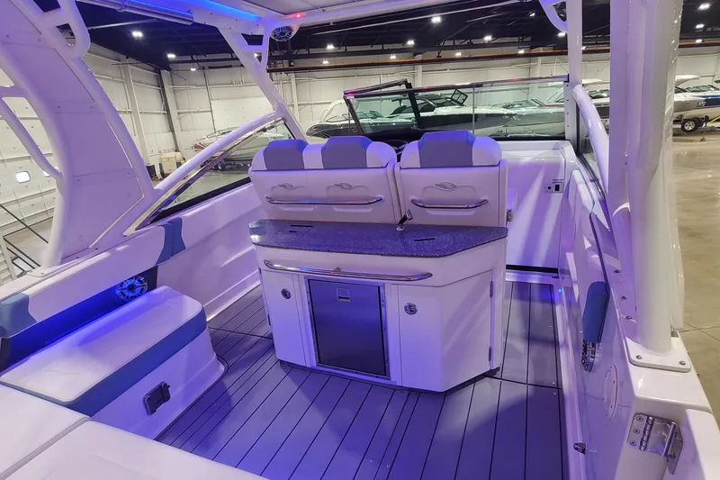 Slide: The Image of 2023 Chaparral 300 OSX boat interior with seating and kitchenette in a showroom. - 49
