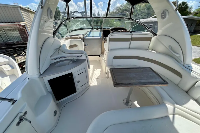 Slide: The Image of 2005 Sea Ray Sundancer 320 interior with seating, table, and helm under clear skies. - 19