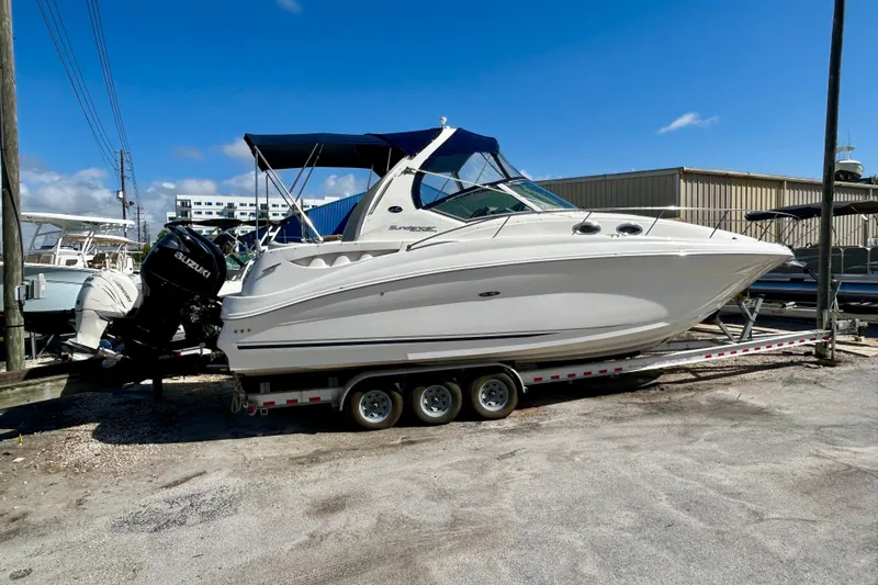 Slide: The Image of 2005 Sea Ray Sundancer 320 boat on trailer, parked outdoors under clear sky. - 2