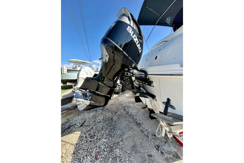 Slide: The Image of 2005 Sea Ray Sundancer 320 with Suzuki outboard motor, docked on gravel surface. - 3