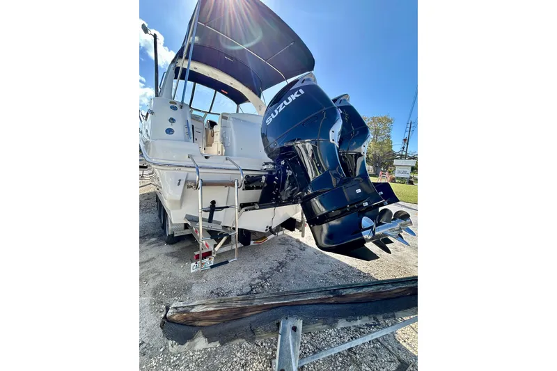 Slide: The Image of 2005 Sea Ray Sundancer 320 with Suzuki outboard motor, parked on gravel. - 5
