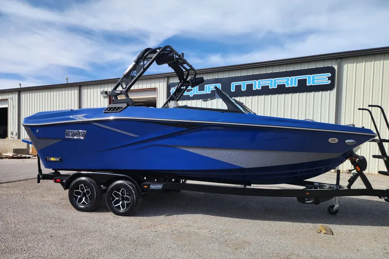 The Image of 2026 Heyday H22 boat in vibrant blue on a trailer outside a marine shop. - 0