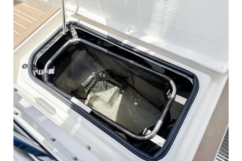 Slide: The Image of An open storage compartment on a boat with a mesh basket inside. - 21