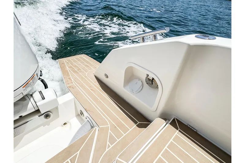 Slide: The Image of The image shows the stern of a 2024 Windy SR28 CC boat with teak decking and motor. - 19