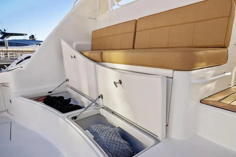 Slide: The Image of 2012 Cabo 44 Hardtop Express boat with cushioned seating and open storage compartments. - 15