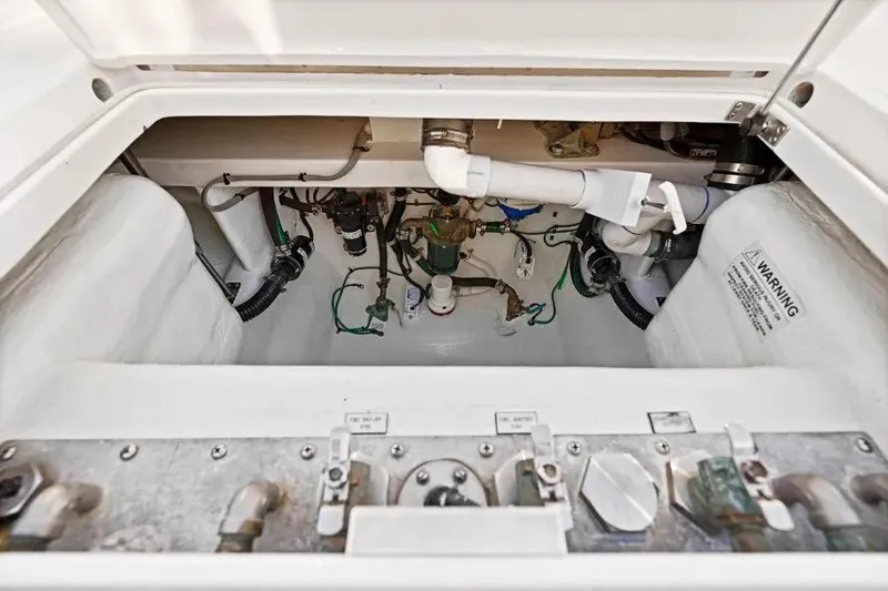 Slide: The Image of Engine compartment of 2012 Cabo 44 Hardtop Express boat, showing mechanical components and warning label. - 17