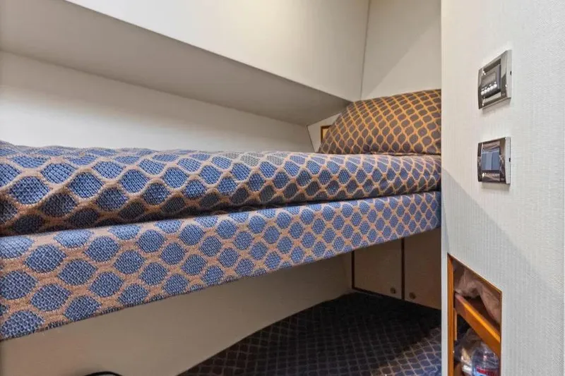 Slide: The Image of 2012 Cabo 44 Hardtop Express cabin with patterned bedding and storage shelves. - 20