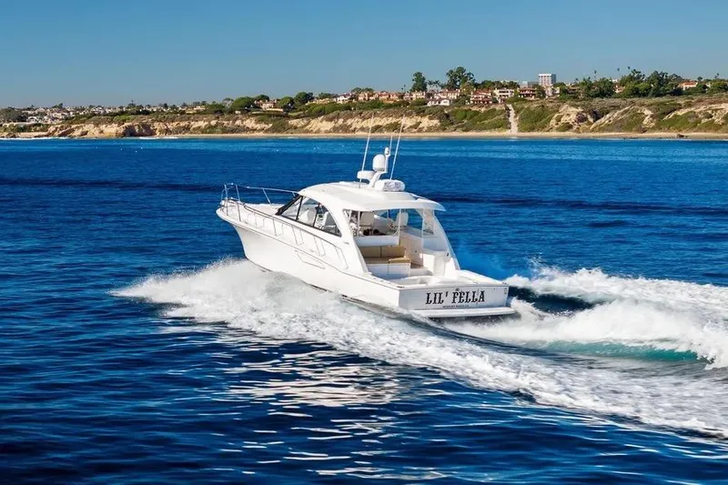 Slide: The Image of 2012 Cabo 44 Hardtop Express yacht cruising on blue ocean near scenic coastline. - 37