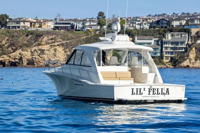 Slide: The Image of 2012 Cabo 44 Hardtop Express yacht on water near coastal homes. - 41