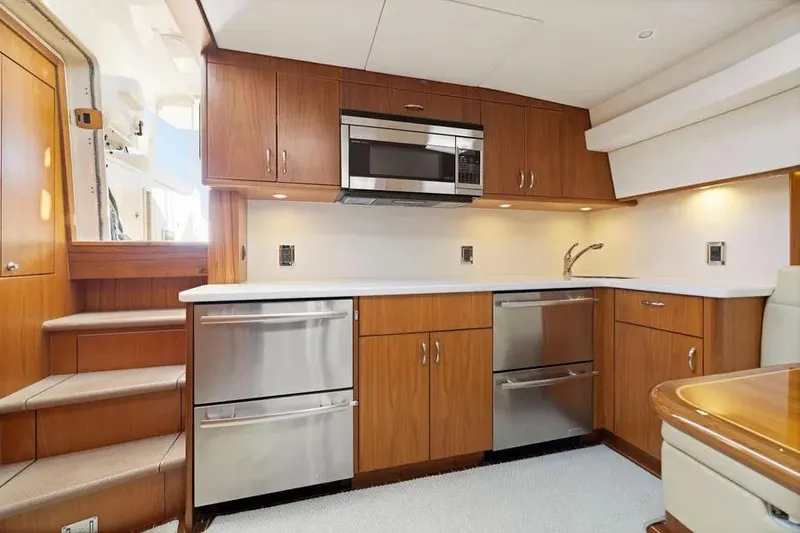 Slide: The Image of Luxurious 2012 Cabo 44 Hardtop Express yacht kitchen with modern appliances and wood cabinetry. - 6