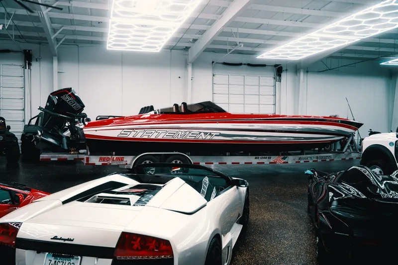 Slide: The Image of Red Statement 360 CAT boat on trailer in garage with luxury cars. - 20