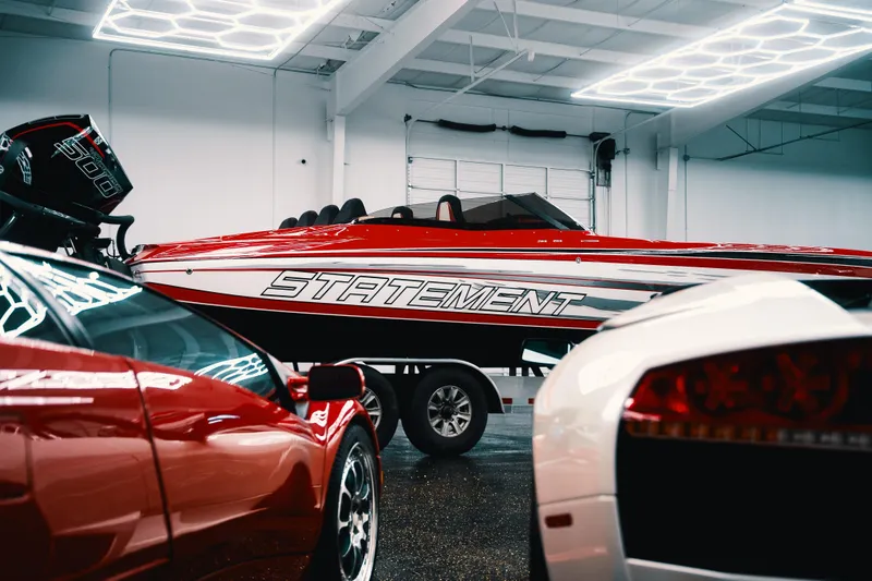 Slide: The Image of Red and white Statement 360 CAT boat in showroom, surrounded by luxury cars. - 21
