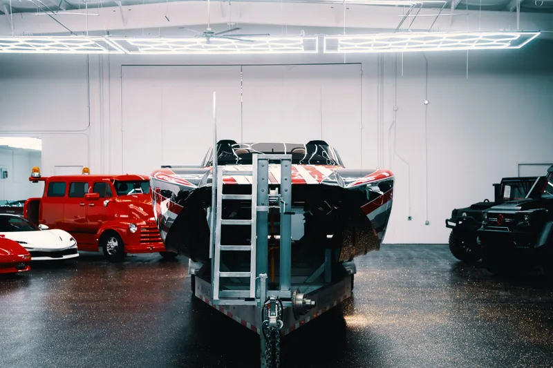 Slide: The Image of 2025 Statement 360 CAT boat in showroom with vintage and luxury vehicles. - 3