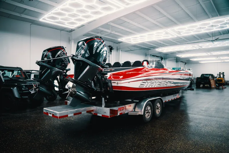 Slide: The Image of Red and white Statement 360 CAT boat with dual engines on a trailer in a garage. - 6