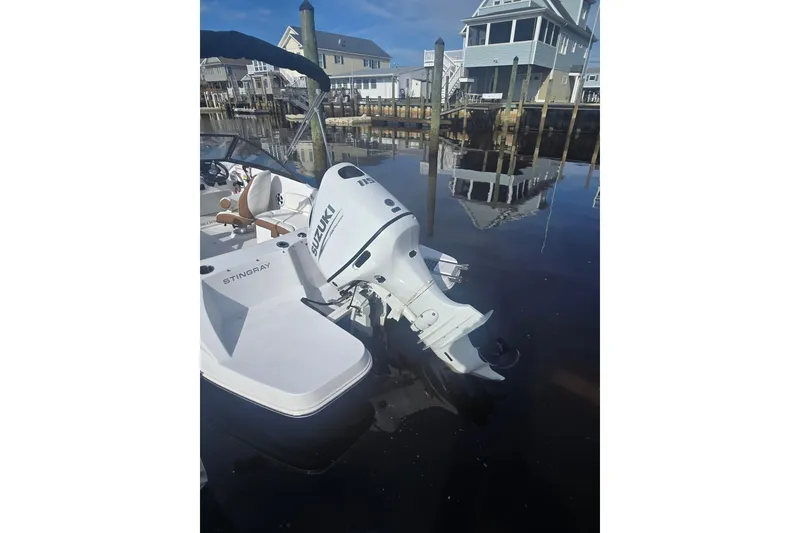 Slide: The Image of 2025 Stingray 191 DC boat with Suzuki outboard motor docked by waterfront homes. - 5