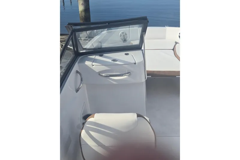 Slide: The Image of 2025 Stingray 191 DC boat interior with seating and windshield, docked by calm water. - 6