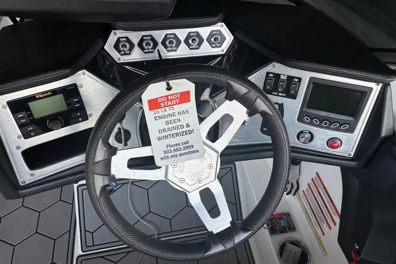 Slide: The Image of 2018 MasterCraft NXT22 dashboard with steering wheel, controls, and winterization warning tag. - 9