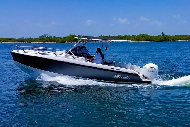Slide: The Image of A 2024 Windy SR28 CC boat cruising on calm waters with a Yamaha outboard motor. - 0