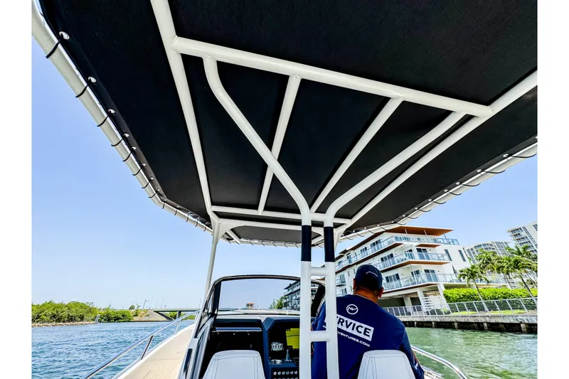 Slide: The Image of A modern boat with a black sunshade and a service crew member steering it. - 11