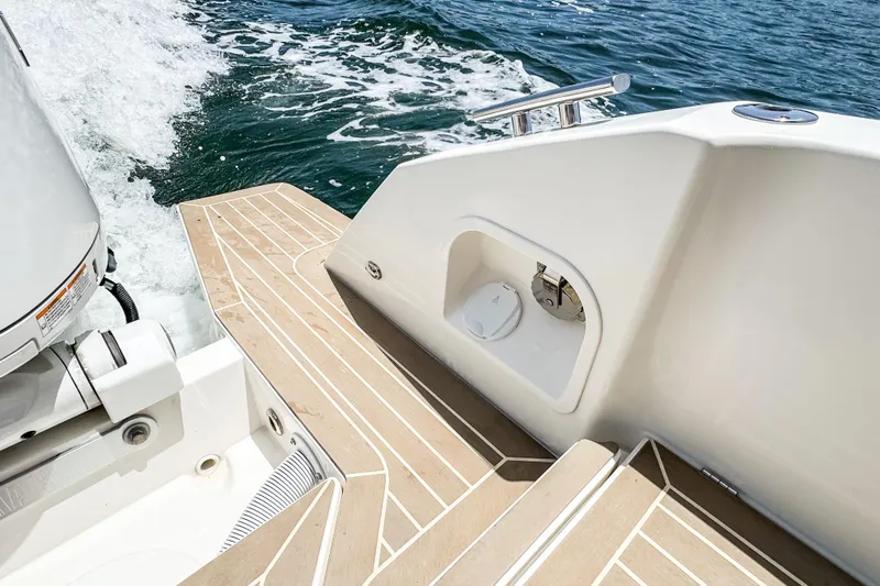 Slide: The Image of The image shows the stern of a 2024 Windy SR28 CC boat with wooden decks and motor. - 19