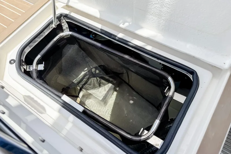 Slide: The Image of An open storage compartment on a 2024 Windy SR28 CC boat with a mesh basket inside. - 21