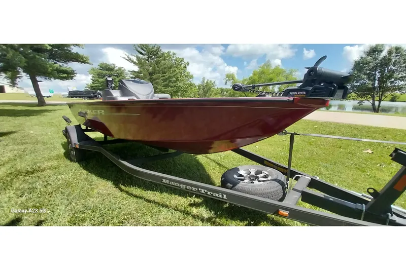 The Image of 2025 Tracker Super Guide V-16 SC boat on trailer, parked on grass near a lake. - 0