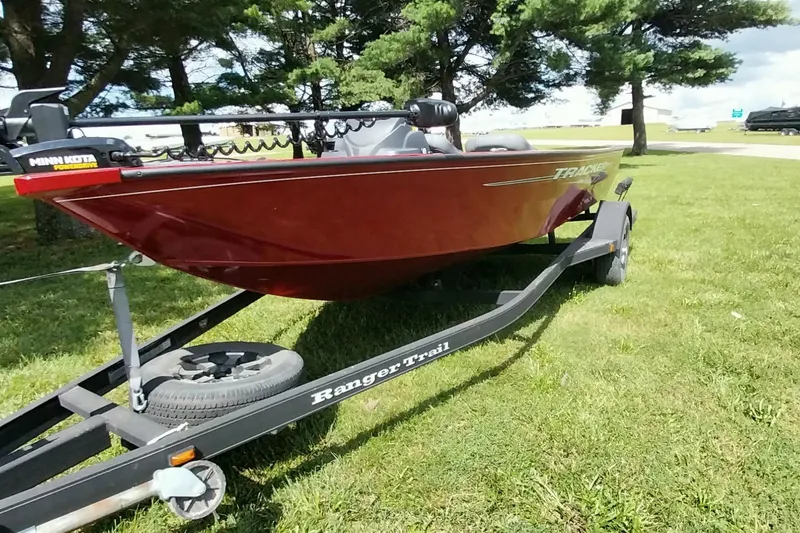 Slide: The Image of 2025 Tracker Super Guide V-16 SC boat on a trailer, parked on grass. - 12