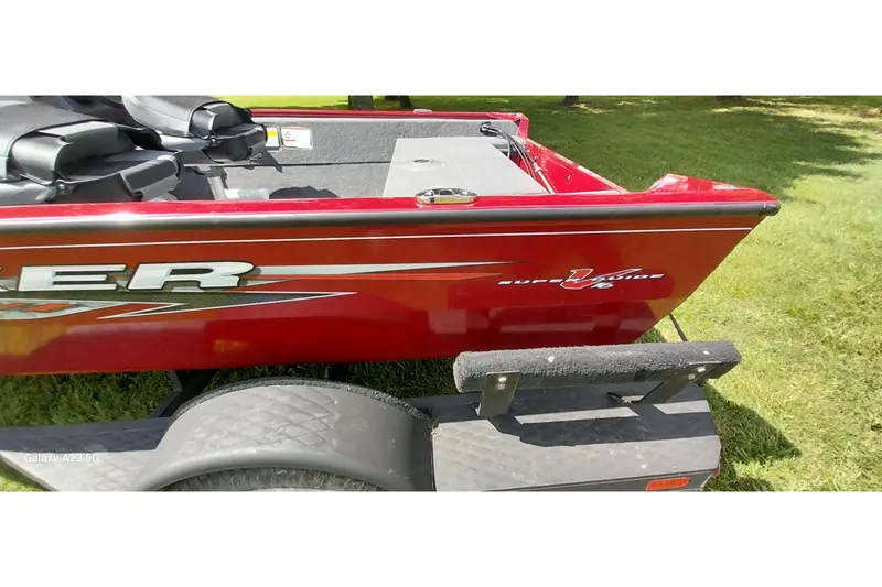 Slide: The Image of Red 2025 Tracker Super Guide V-16 SC boat on trailer, parked on grass. - 18